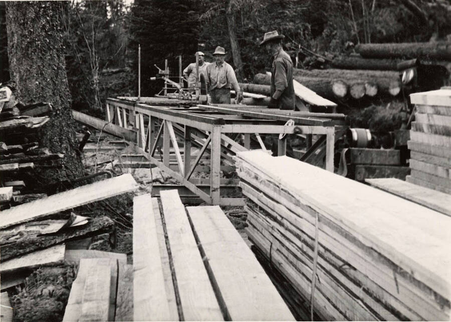 Three men work on a piece of machinery at the McMamm Mill on Harrish Ridge.