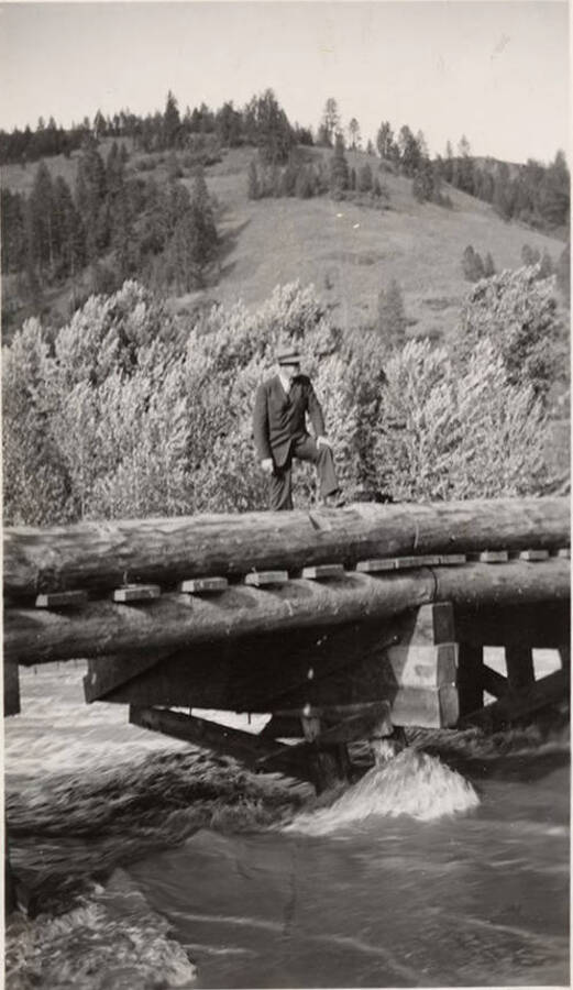 A man stands on Stites Bridge while the river rushes below.