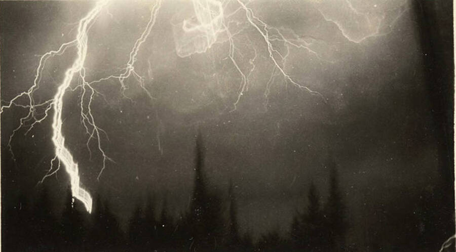 Lightning bolts light up the sky with trees in the background. Written on the envelope 'brush disposing and burn - lightning-airplane.'