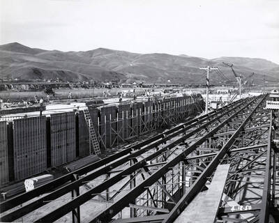 Men work on the roof of one of the buildings under construction at the Clearwater Mill while on the on the right hand side is also under construction. The date written on the photograph is 4/12/1950.