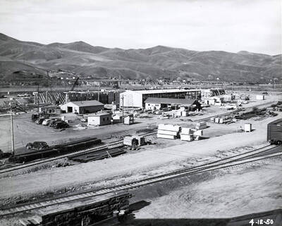 Several of the Clearwater mill's buildings under construction. In the foreground, stacks of lumber sit next to train tracks. The date written on the photograph is 4/12/1950.