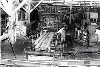 A man works with planks at a gang saw.