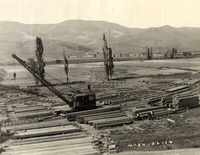 A crane sits surrounded by piles of lumber. The writing on the side of the crane reads 'Clearwater Timber Co. Loco crane No.1.' Written on the photograph is '4/24/26 No. 14.'