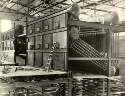 According to the description on the back of the photograph, looking at the machinery of the planing mill.