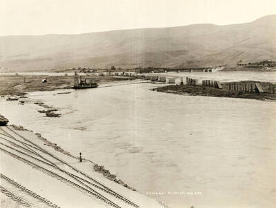 A view of the log pond from Forebay. A boat moves across the water in the middle of the of the photograph. Written on the photograph is 'Fore Bay 5/18/1927 No. 272.'