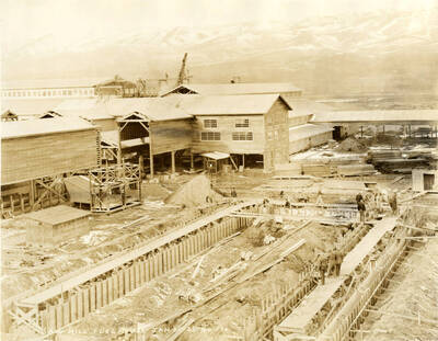 Construction of the sawmill fuel house. Men work on the back and right hand side of the building. Written on the building 'Saw Mill Fuel House 1/25/1927 No. 186.'
