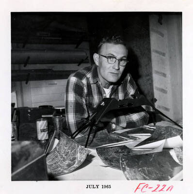 A forest researcher uses a stereoscope and aerial photographs to help study the forests