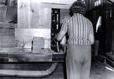 A woman works with planks of lumber.