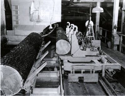 One rough log sits, waiting for the machine to finish with another log.