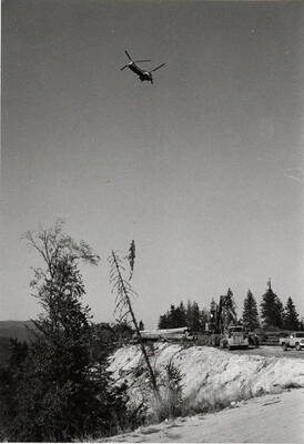 A Vertol twin rotor helicopter flies a load of logs to the log deck.