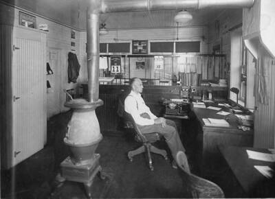Chet Younger sits in the Elk River warehouse. Behind him is a stove used to heat the room.