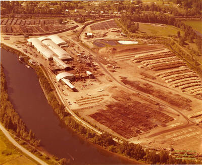 The plywood plant at St. Maries, Idaho. In the picture is the St. Joe River (left side of the photograph) and the decks of logs waiting to be processed (right side of the photograph).