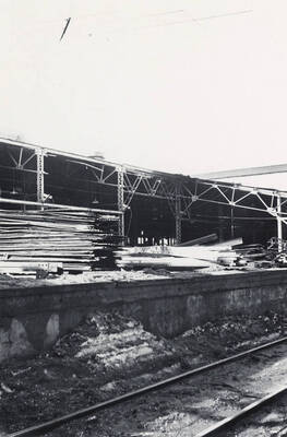 Lumber piled outside of a shed.