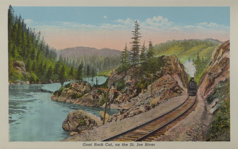Postcard is part of a postcard packet. Image is of a train in a river canyon near St. Joe, Idaho.