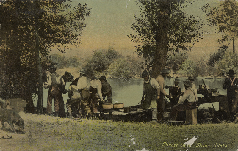 Postcard of men having a meal next to a river in Idaho.