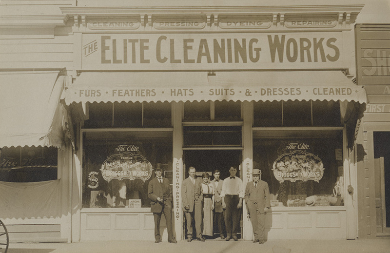 Postcard of men posing in front of a shop likely in Lewiston, Idaho.