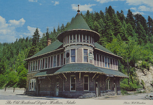 Postcard of the Old Railroad Depot in Wallace, Idaho.  | Bricks originally imported from China in 1890, by the Northern Pacific Railway Co., were once a part of a building meant to be one of the World's greatest hotels, the Olympic in Tacoma, Washington. The hotel was never finished and was dismantled for use in several depots. 15,000 bricks were used to build this chateau-like depot, which has stood as a focal point in Wallace since 1902. It is now owned and operated by the Burlington Northern Railroad, and was featured in the popular movie "Heaven's Gate," part of which was filmed in Wallace.