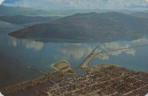 Postcard is an aerial photograph of Sandpoint Idaho and Lake Pend Orielle. | Sandpoint, Idaho. The matchless beauty of Sandoint on Pend Oreille Lake, 43 miles long, 111 miles of shore. Home of fishing greatest - The Giant Kamloop. Free public beach in center with boat launching facilities, swimming, water skiing, concessions, free bath house and picnic area. Lower center shows water highway from lake to center of city. Modern stores - Trading center of Northern Idaho. Three bowling alleys, golf course. Ultra Motel accommodations, transportation by three railroads, municipal airport, bus line. Family Fun - All Day - Every Day. Only 70 miles to Spokane.