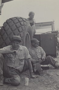 Postcard of men and women eating next to a truck near Moscow, Idaho. | Lunch in the shade of a combine during pea harvest, August. This photograph is one of the many striking images of Palouse farm life included in Bill Woolston's Harvest. A hardbound, 128-page book published by Thorn Creek Press, Genesee, Idaho, 83832, Harvest is available in your local bookstore or direct from the publisher.