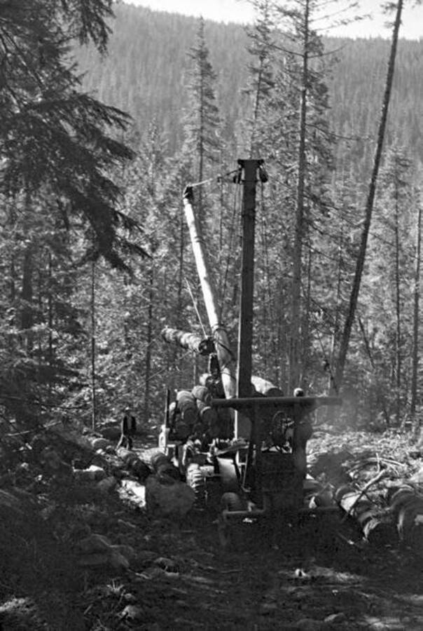 Workers using machinery to load logs onto a truck at Camp #9. Donated by Speed Weidner through Priest Lake Museum.
