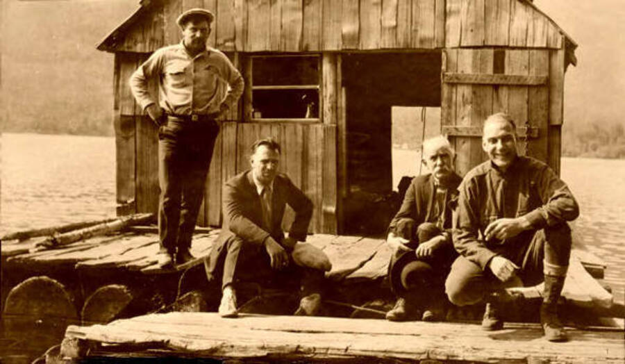 Four men posed outside the 'Daddy' Duffill house. Stanley Jones is the one standing. Donated by Marjorie Paul Roberts via Priest Lake Museum.