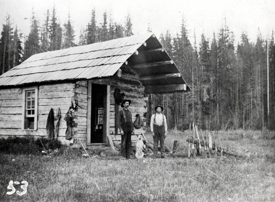 Ed Geugler and Frank Lilya stand outside a cabin.
