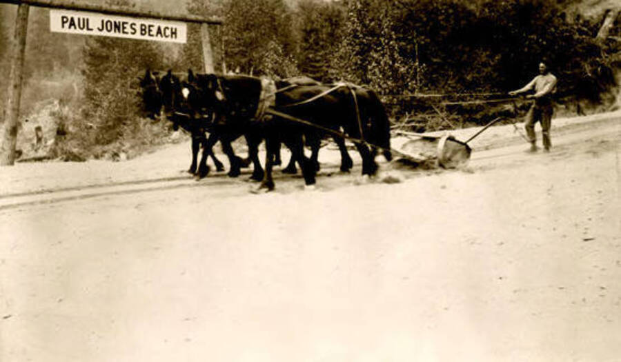 A team of horses pulling sand down to the marina area from Leonard Paul store. Coolin, Idaho. Donated by Marjorie Paul Roberts via Priest Lake Museum.