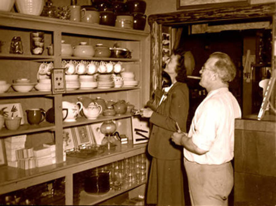 Leonard Paul inside his store with a customer looking at glassware. Donated by Marjorie Paul Roberts via Priest Lake Museum.