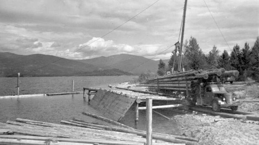 View of Kalispell Bay loading dock. Truck #6 loaded with poles. Donated by Lee White through Priest Lake Museum.