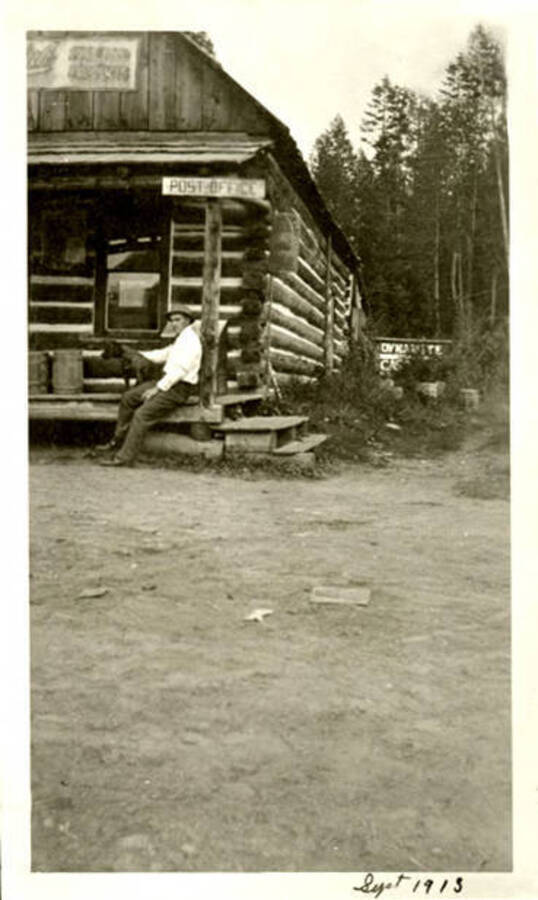Leonard Paul sitting with a dog on the porch of his first store. Coolin, Idaho. Donated by Marjorie Paul Roberts via Priest Lake Museum.