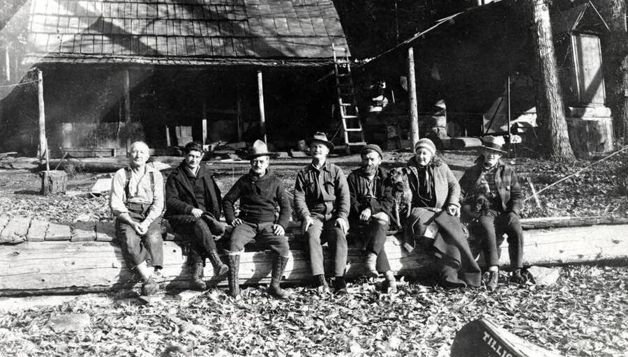 Pictured are Lewis 'Pete' Chase, Bob White, Frank Algren, Frank Brown, Gustav Johnson, Maude Whitacre, and Dick Collier. A dog is also present.