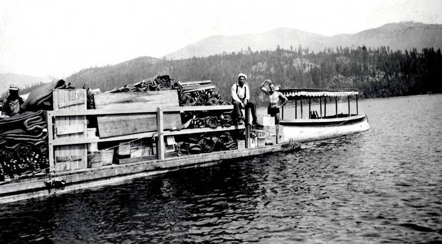 Three men on a barge pushed by the launch Firefly.