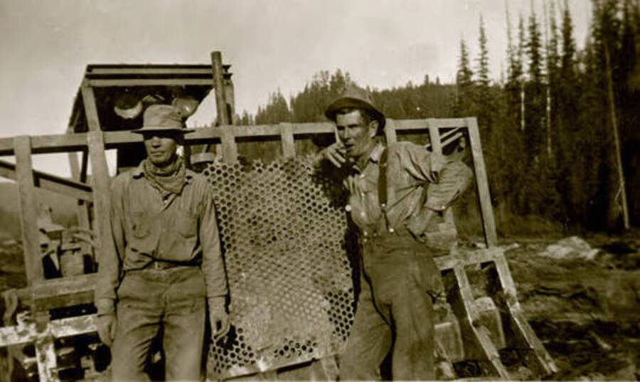 Two workers standing in front of machinery in Hughes Meadow. Donated by Red Gasterneau through Priest Lake Museum.