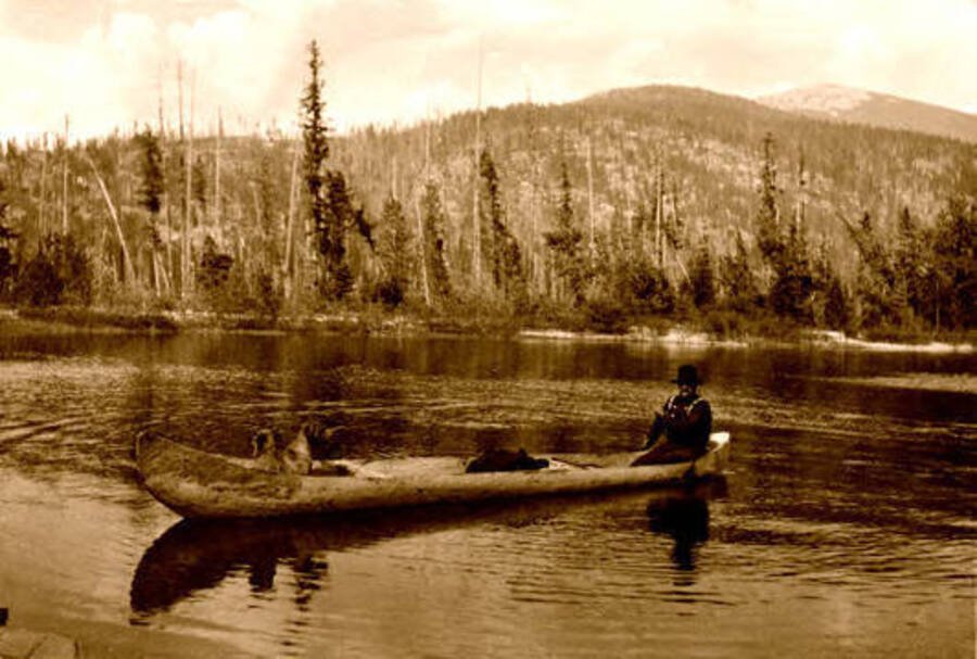 A man and a dog in a canoe. Priest Lake, Idaho. Donated by Harriet (Klein) Allen via Priest Lake Museum.