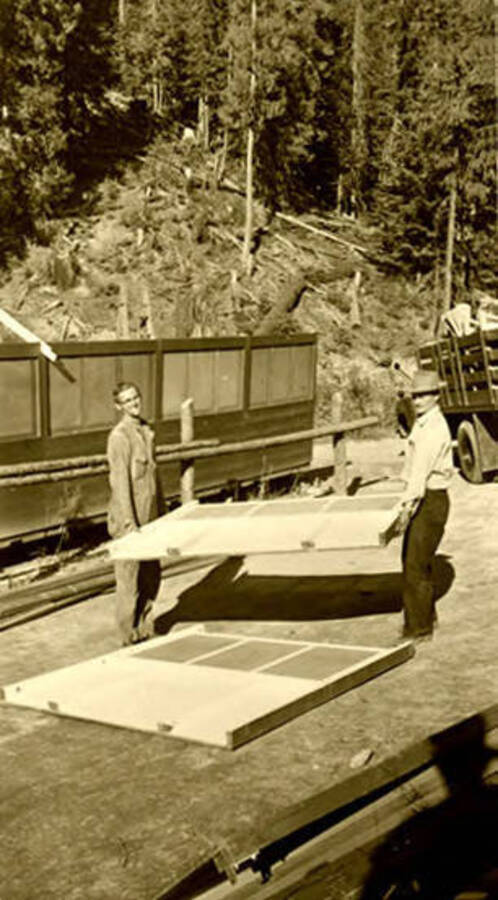 Two workers carrying sections of siding. Donated by Red Gasterneau through Priest Lake Museum.