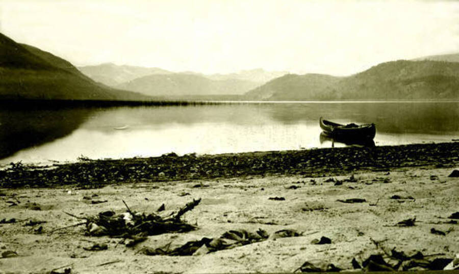 View of Priest Lake with a canoe sitting on the beach. Donated by Margaret Randall through Priest Lake Museum.