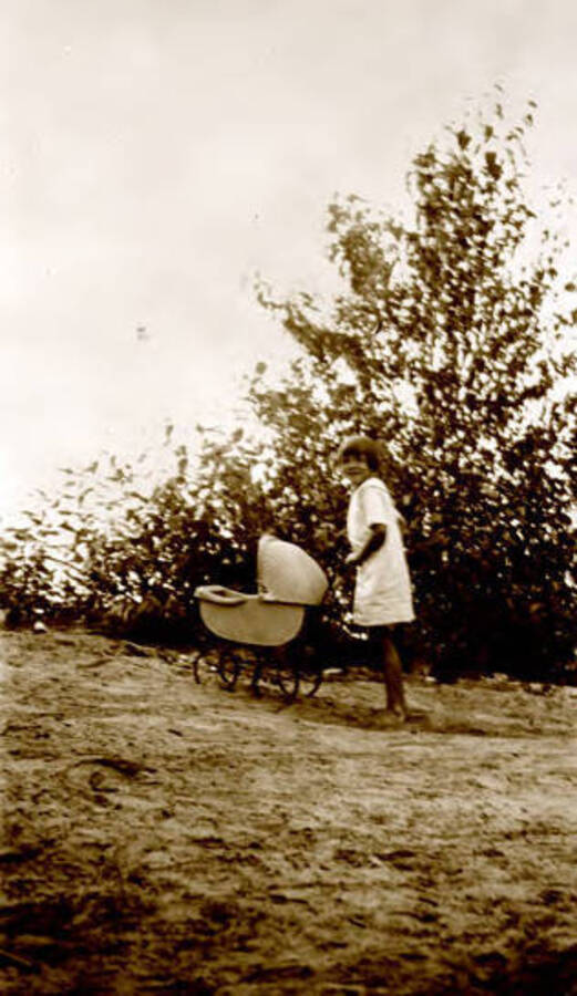 Margaret Calfee Randall with a doll buggy going up a hill. Donated by Margaret Randall through Priest Lake Museum.