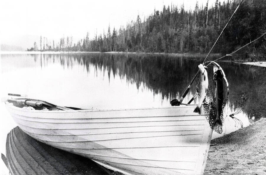 Fish, net, and pole at the bow of beached boat. Donated by Harriet (Klein) Allen through Priest Lake Museum.