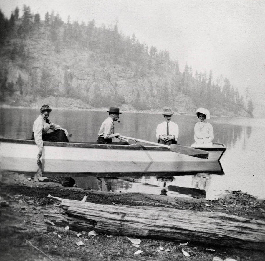 Two men and two women sitting in a rowboat near the beach. Donated by Harriet (Klein) Allen through Priest Lake Museum.