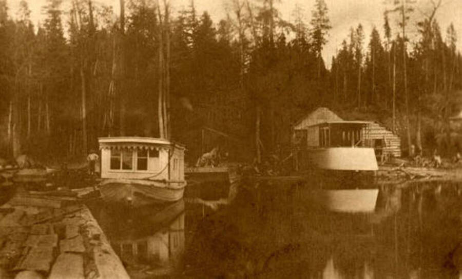 Building the W. W. Slee (steamboat). The Kaniksu is tied up to the dock. The Kaniksu was the first powered boat on Priest Lake, started running there in 1896. Owned by Walter W. Slee. Donated by Harriet (Klein) Allen via Priest Lake Museum.