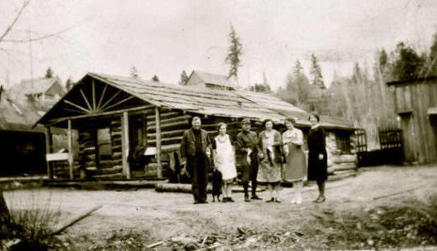 Six people standing in front of the Warren cabin and homestead. Coolin, Idaho. Donated by William Warren through Priest Lake Museum.