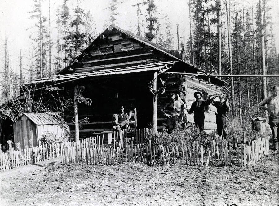 Five hunters and a dog in front of the Edward 'Dad' Moulton cabin. Donated by Harriet (Klein) Allen through Priest Lake Museum.