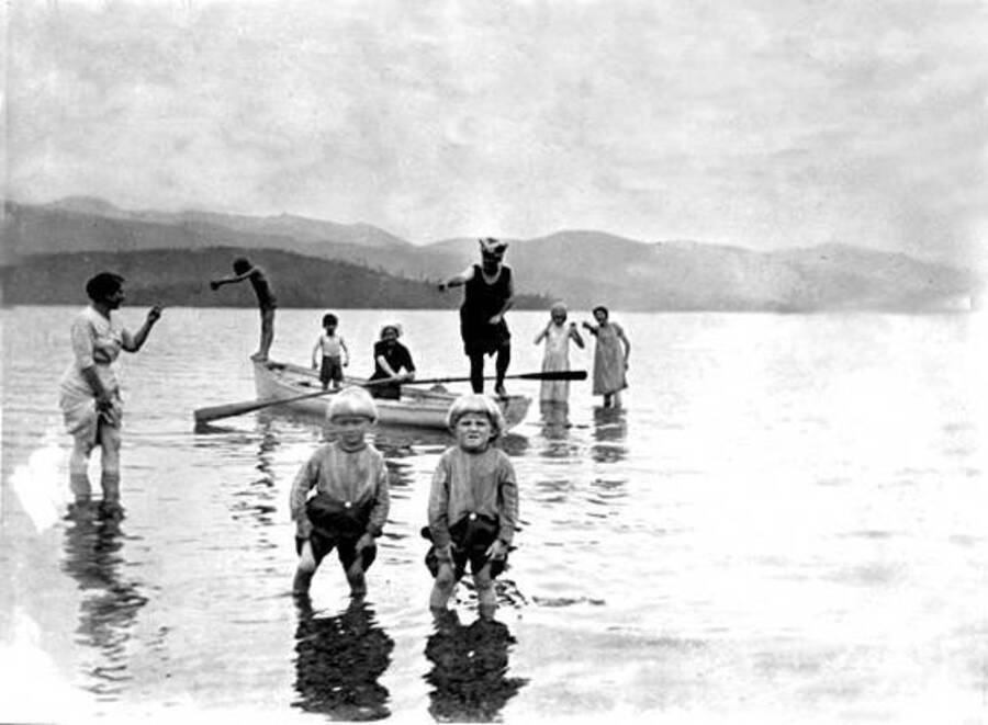 Frosty and Scotty knee deep in water. Other swimmers can be seen in the background. Donated by Mike Winslow through Priest Lake Museum.