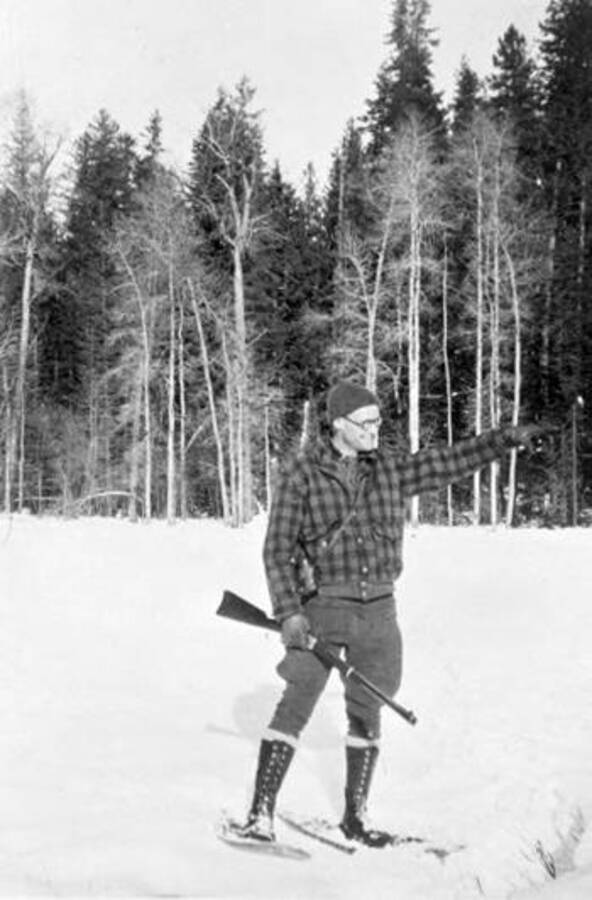 Graydon Winslow carrying a gun while wearing snowshoes. Donated by Mike Winslow through Priest Lake Museum.