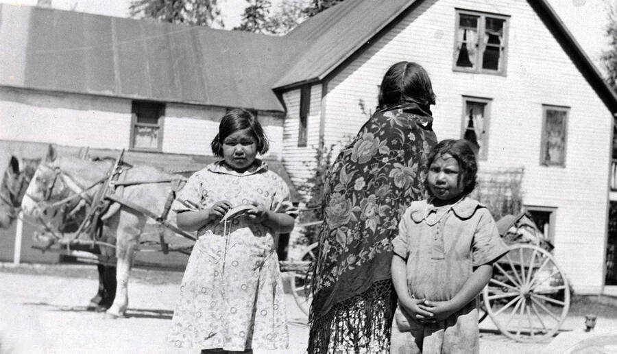 Three Indigenous girls in standing outside the Idaho Hotel. Coolin, Idaho. Donated by Marjorie (Paul) Roberts through Priest Lake Museum.
