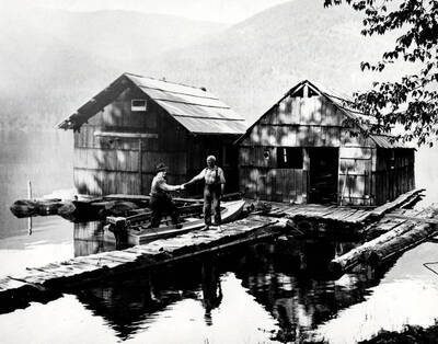 Lewis 'Pete' Chase standing on a dock shaking hands with an unidentified man in a boat.