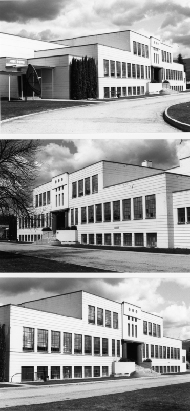 A large, multi-level building with numerous windows and a central entrance. There are steps leading up to the entrance, flanked by shrubs. The building has an attached structure labeled "Auditorium" with a large satellite dish nearby. A road curves around the building, and trees are visible in the background. The sky is cloudy.