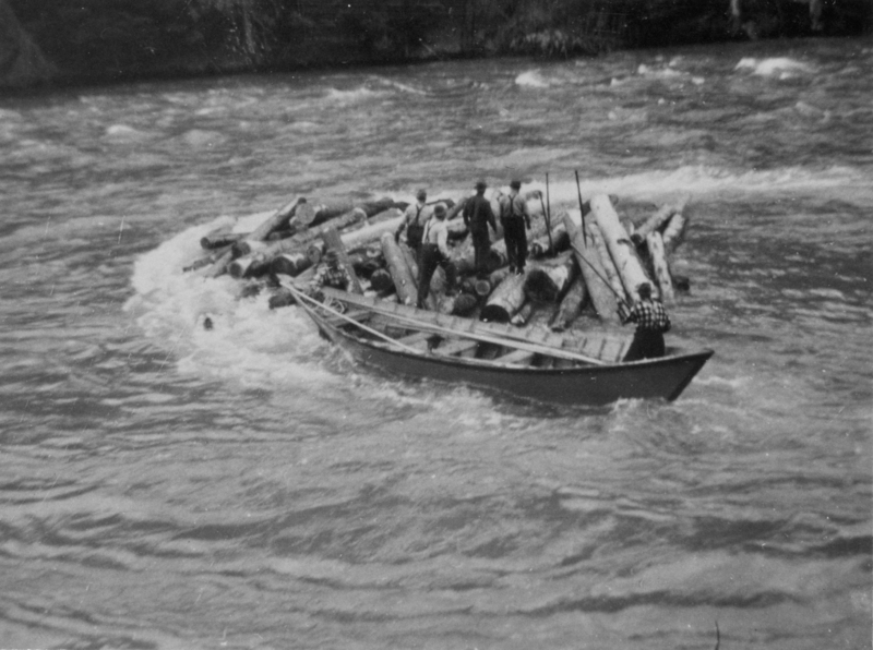 Several people standing on a raft made of logs in a river, with one person at the edge holding a pole.