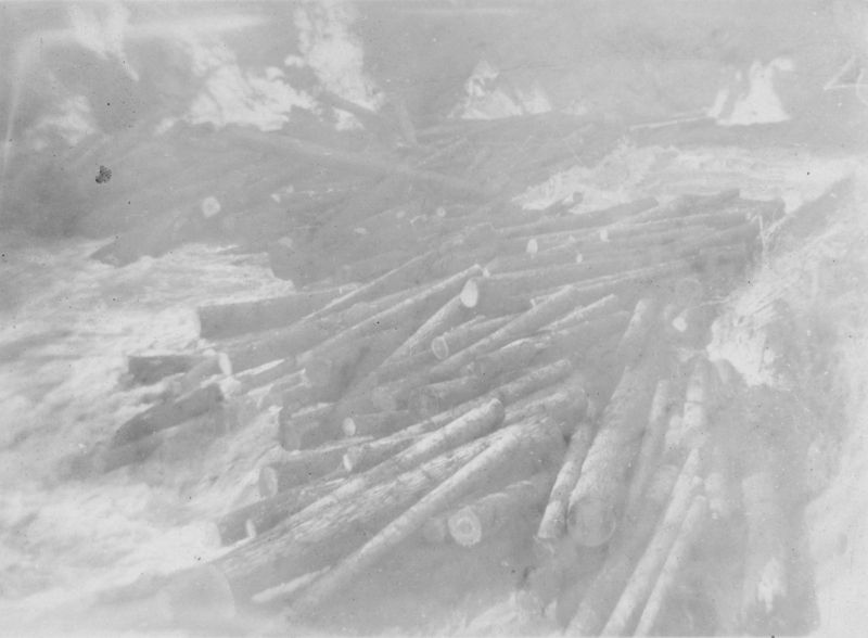 A very faded photo of a log jam on a river.