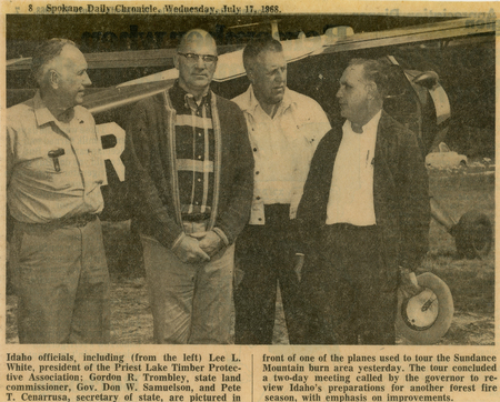 Four men standing beside an airplane, engaged in conversation. Each man is dressed in casual, business attire. One man is holding a hat in his hand. Typed text: Top left: “Spokane Daily Chronicle Wednesday, July 17, 1968.” Bottom section: “Idaho officials, including (from the left) Lee L. White, president of the Priest Lake Timber Protective Association, Gordon R. Trombley, state land commissioner, Gov. Don W. Samuelson, and Pete T. Cenarrusa, secretary of state, are pictured in front of one of the planes used to tour the Sundance Mountain burn area yesterday. The tour concluded a two-day meeting called by the governor to review Idaho’s preparations for another forest fire season, with emphasis on improvements.”